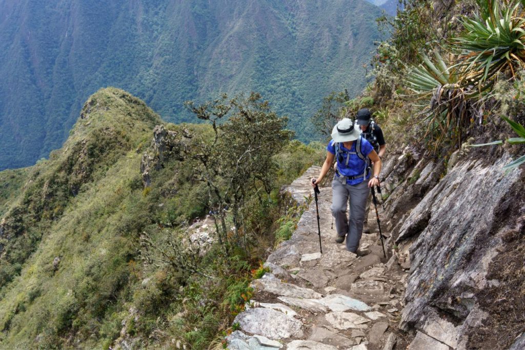 Trekkers on the Inca Trail approaching Machu Picchu through the Sun Gate at sunrise, Peru

